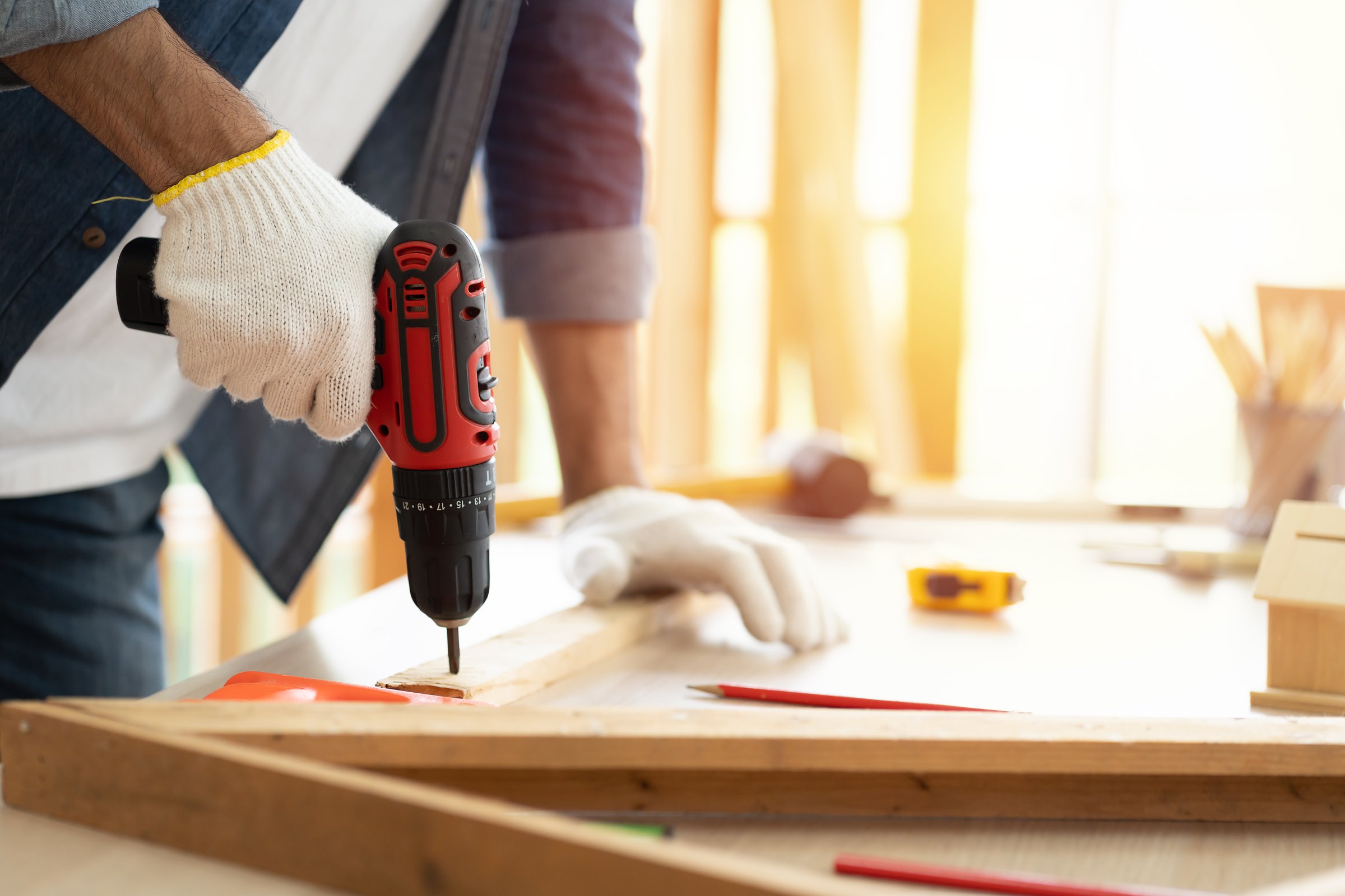 Carpenter using a hand drill to assemble wood in the carpentry shop