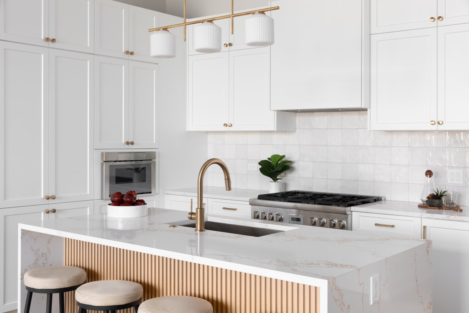Kitchen with white cabinets, tile backsplash, and marble waterfall countertop